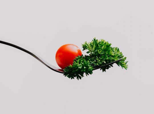 Minimalist close-up of a cherry tomato and parsley on a fork. Perfect for food design.